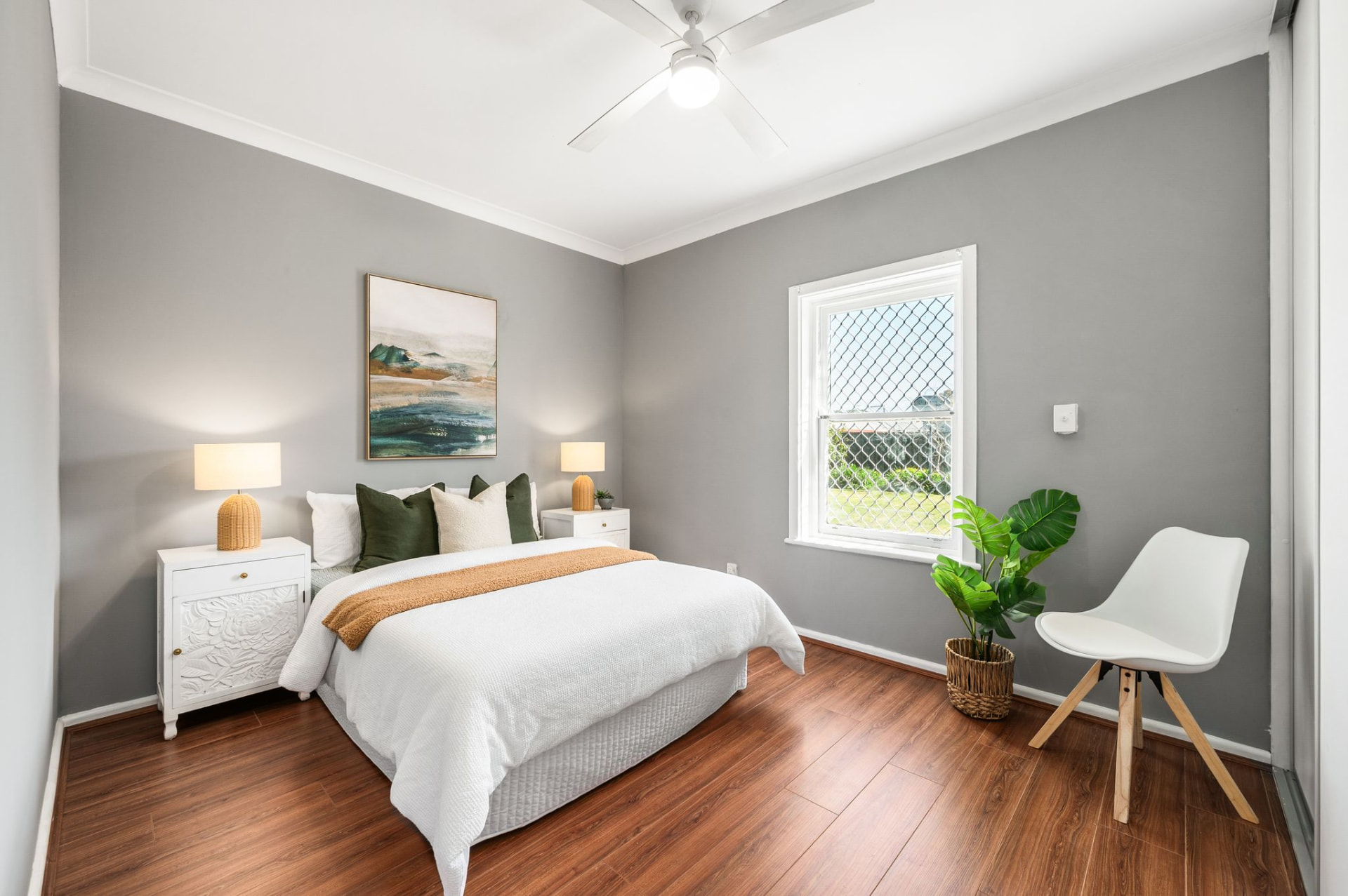 Main bedroom with timber flooring, grey walls and a window overlooking the garden