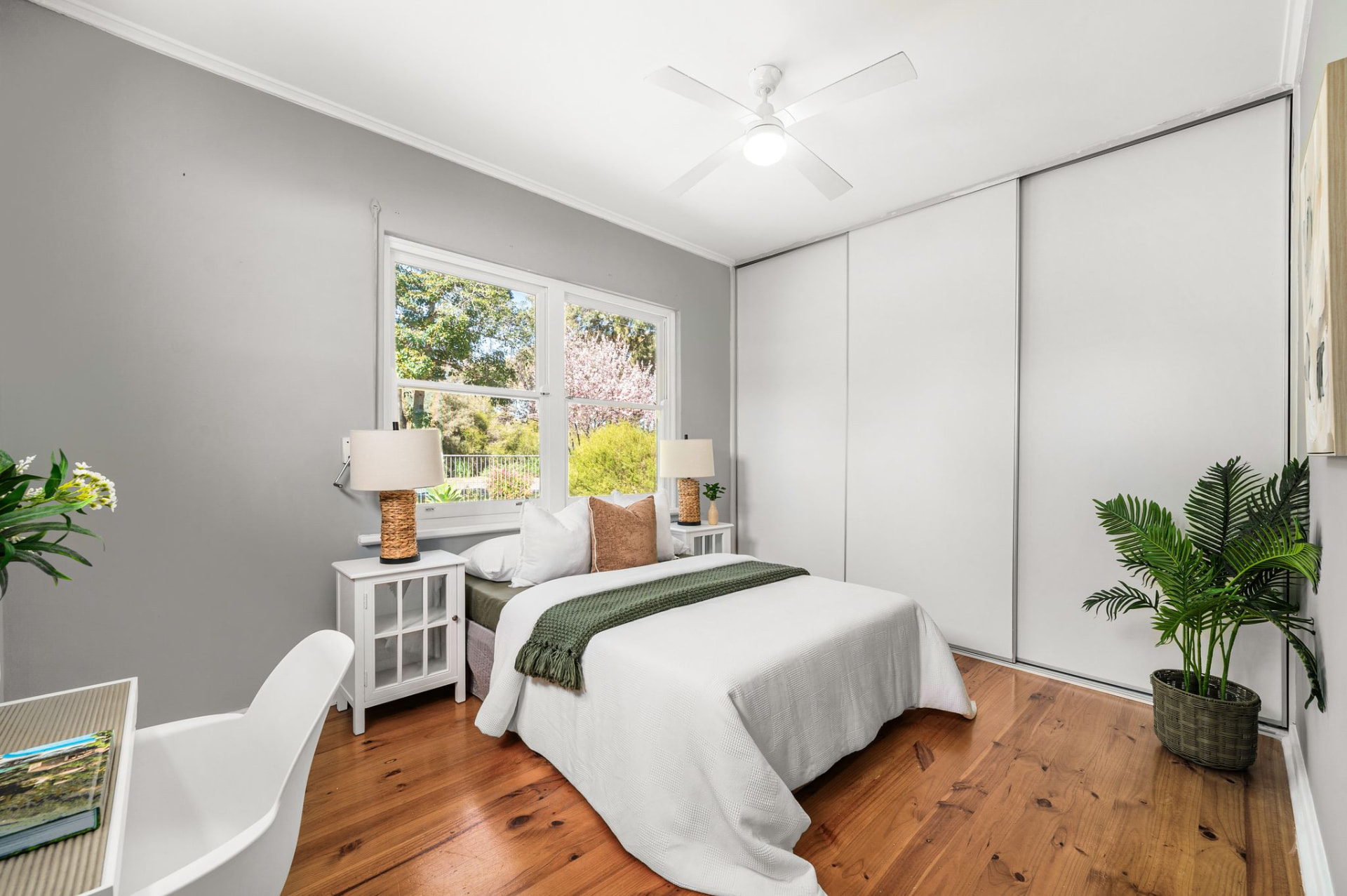 Bedroom with timber flooring, built-in wardrobe and front garden outlook