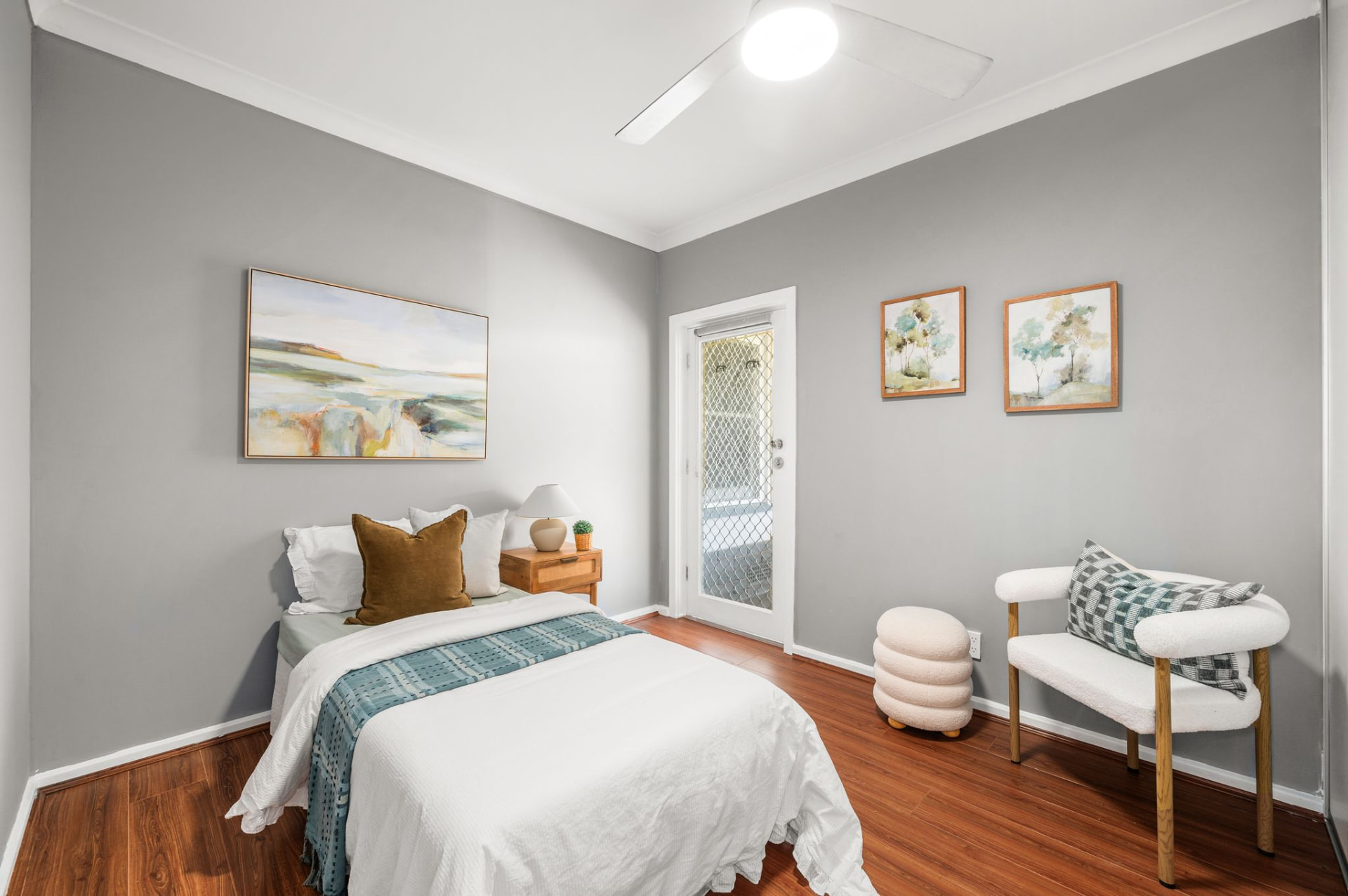 Bedroom with timber flooring, grey walls and access through a glazed door