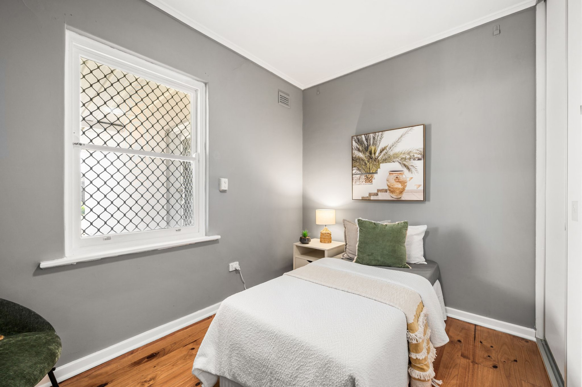 Single bedroom with timber flooring, grey walls and a window